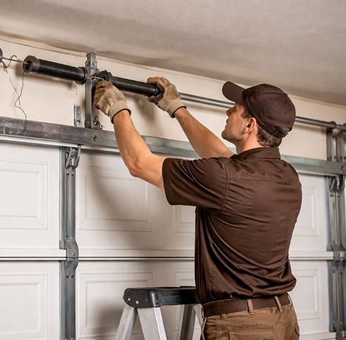Technician repairing a broken garage door torsion spring